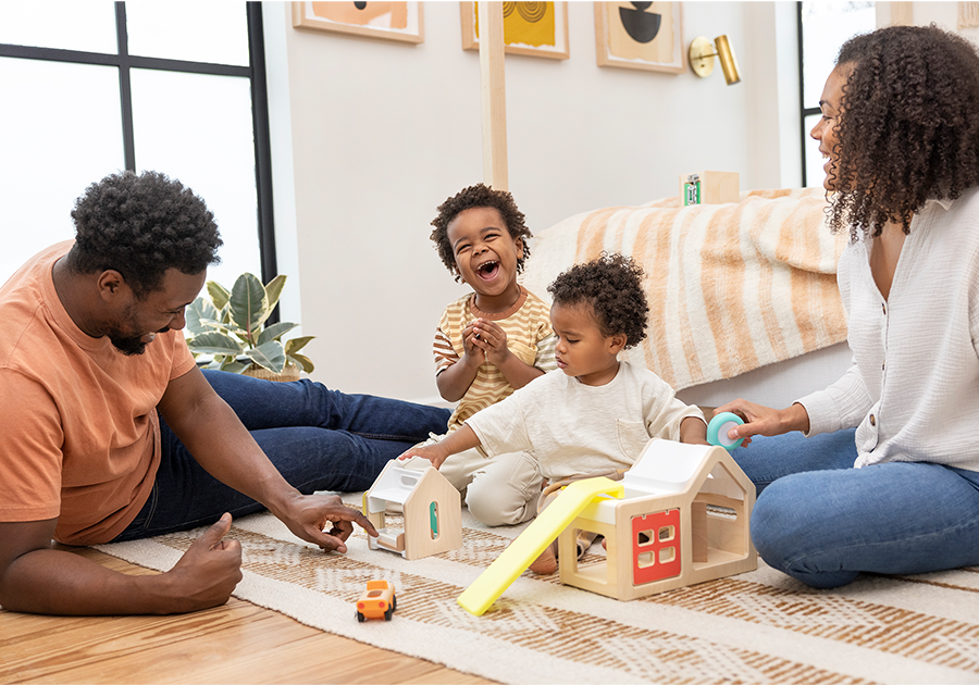 family playing together with young kids toys on living floor